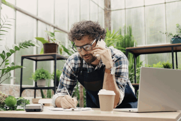 business man talking on the phone with plants behind him